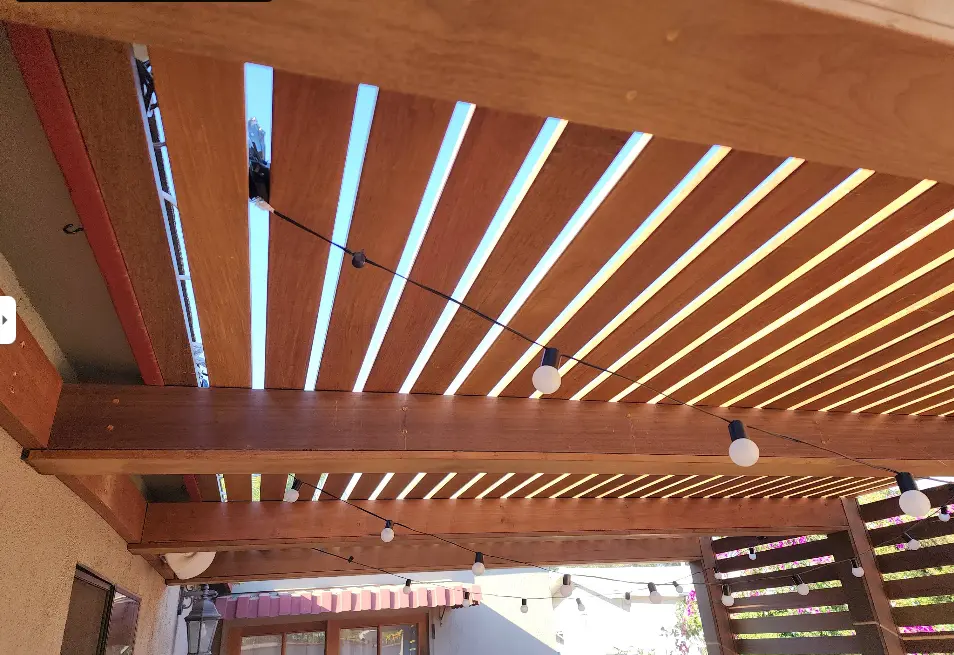 Underside of a stained wood pergola with evenly spaced rafters