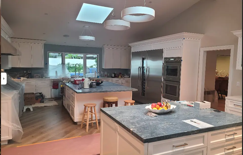 Remodeled kitchen with skylights, white cabinetry and a granite island after repainting