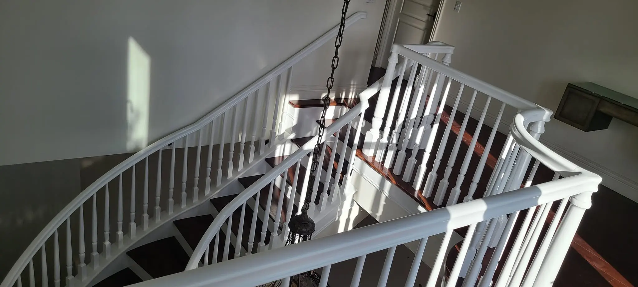 Overhead view of a sweeping curved staircase with fresh white railing paint