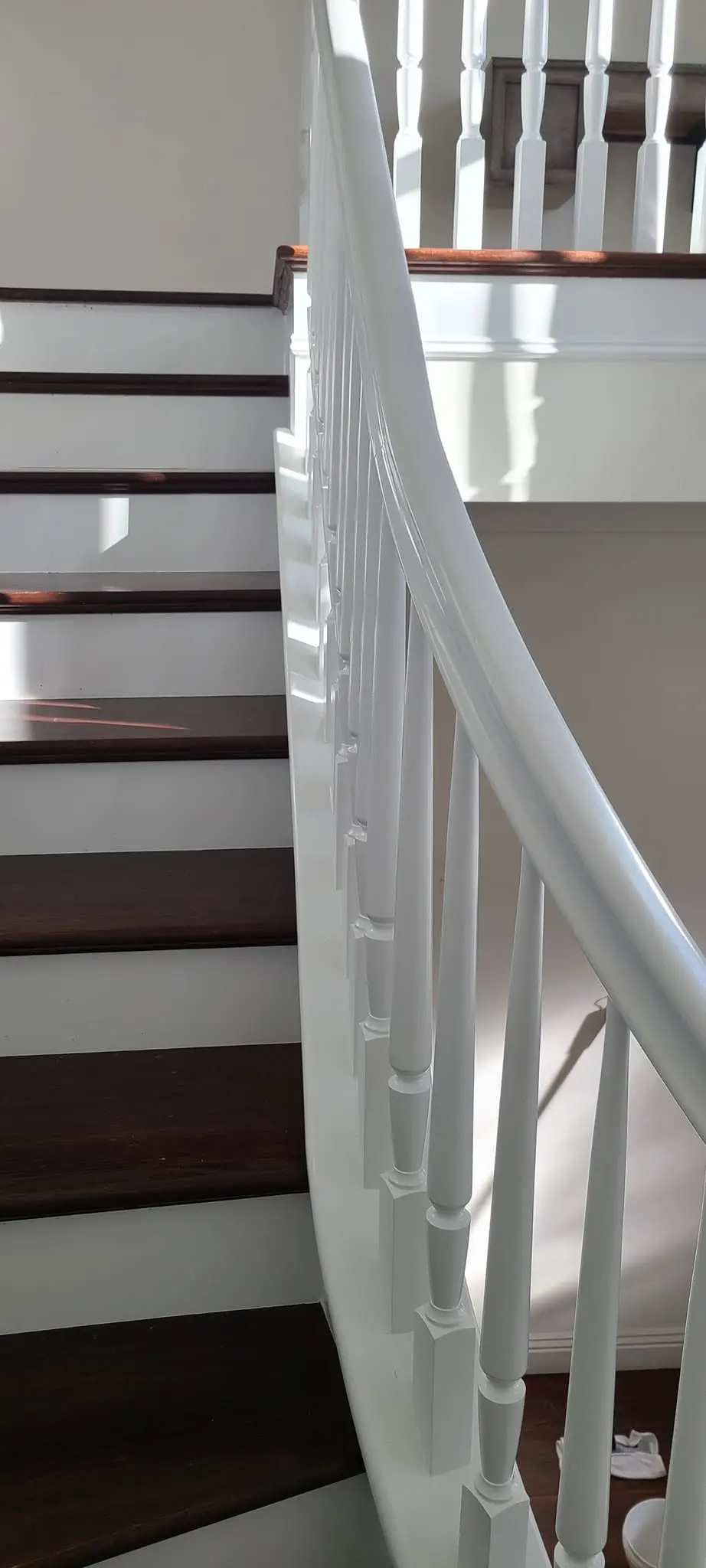 Curved staircase with crisp white railing and hand-painted spindles