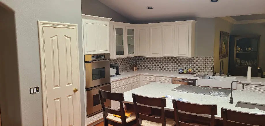 Kitchen with white shaker cabinets and a tile backsplash after cabinet refinishing