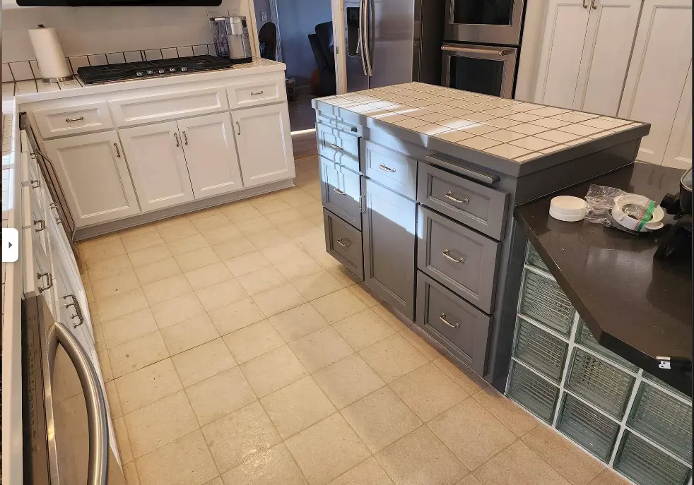 Kitchen cabinets being refinished with a gray-painted island and cream uppers