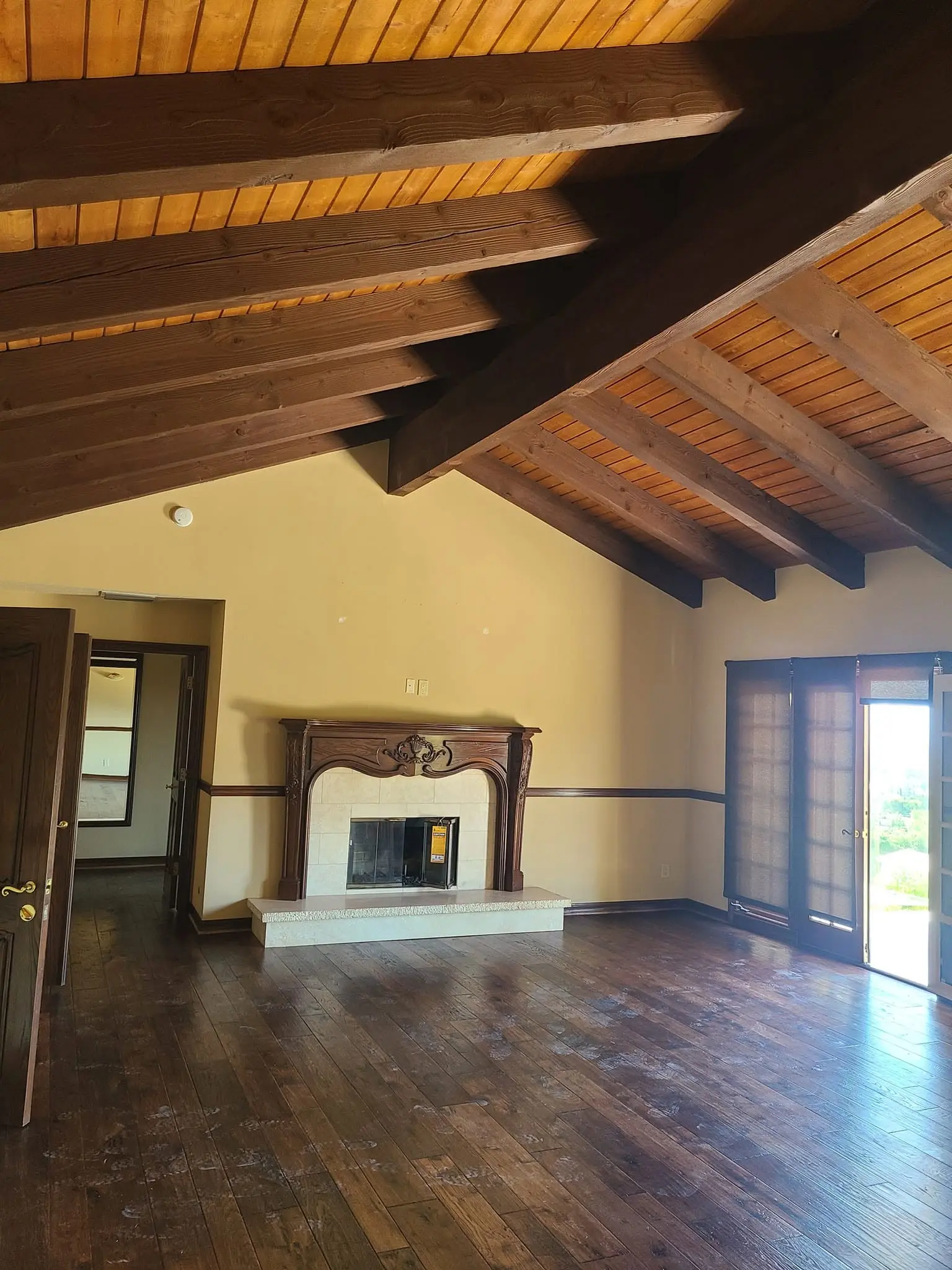 Vaulted stained wood plank ceiling above a marble fireplace in a repainted great room