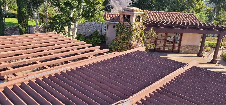 Tile-roof home with a large stained wood pergola over the patio