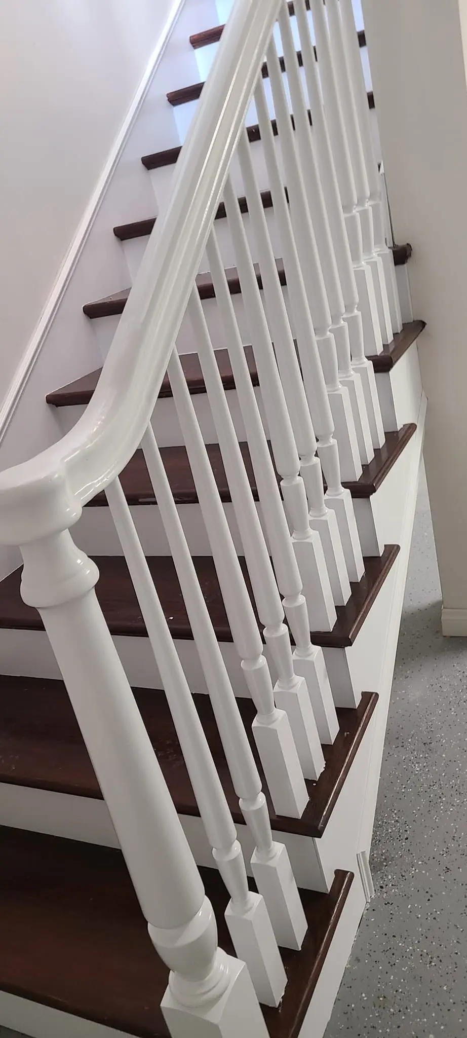 Straight staircase with newly painted white balusters and stained handrail
